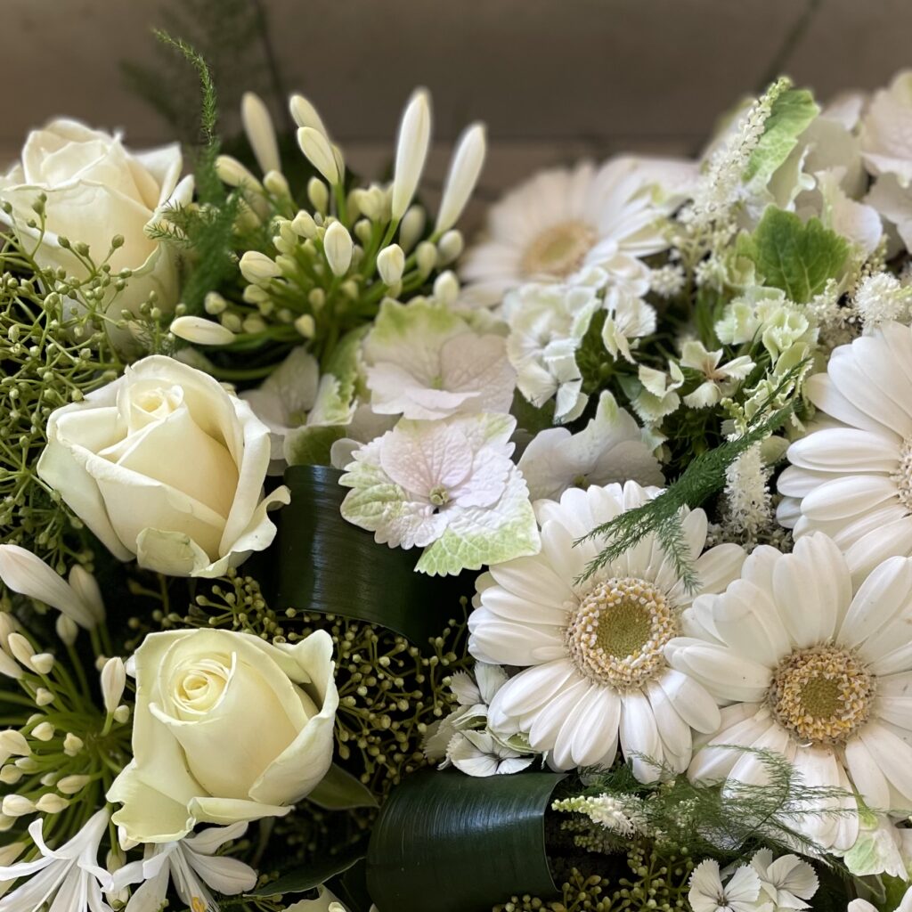 Gros plan d’un bouquet de roses blanches, gerberas et feuillages